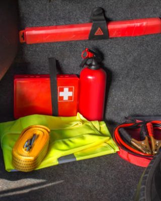 The interior of the trunk of the car in which there is a first aid kit, fire extinguisher, warning triangle, reflective vest, starter cables and tow rope